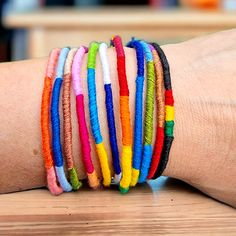 a person's arm with several different colored bracelets on top of each other