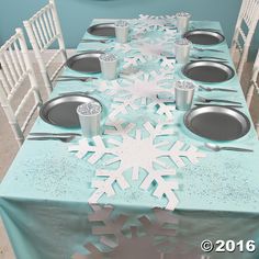 the table is set with silverware and snowflakes on it, as well as plates