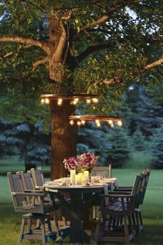 a table and chairs under a tree with lights