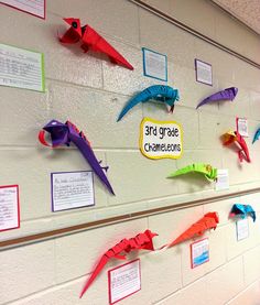 colorful origami birds are hanging on the wall in front of a sign that says 3rd grade crawfish lessons