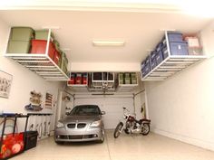 a car is parked in the garage with two shelves above it that hold various items