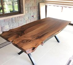 a wooden table sitting on top of a white tile floor next to a brick wall