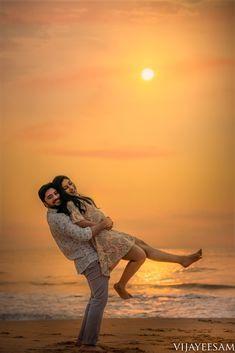 a man holding a woman on the beach at sunset