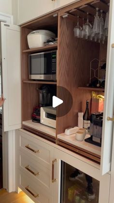 an open cabinet with wine glasses and other items on it in a small kitchen area