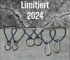 three pairs of scissors hanging from hooks on a concrete wall with the words limitiert 2094 written above them