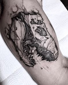 a black and white photo of a man's arm with a dinosaur tattoo on it