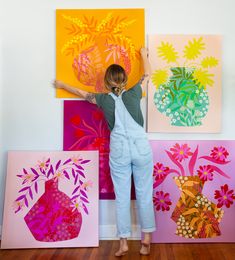 a woman standing in front of several colorful paintings