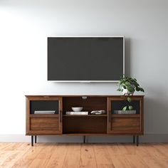 an entertainment center with a flat screen tv mounted on it's wall, next to a potted plant