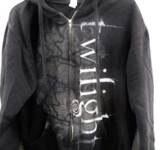 a black hoodie with white writing on the front and back, hanging from a mannequin's head