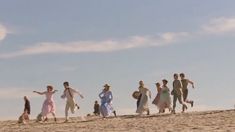 a group of people walking across a sandy beach