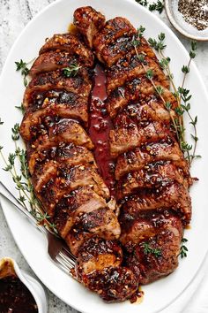 sliced pork chops on a plate with sauce and herbs