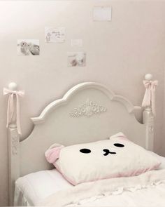 a white bed topped with a pillow covered in pink and white pillows next to a wall