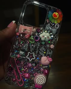 someone is holding up their phone case with many different items on it, including charms