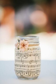 a glass jar with music notes and flowers on it, sitting on a table top