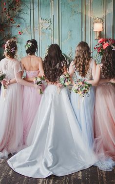 a group of women standing next to each other in front of a wall with flowers