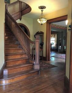 a wooden staircase leading up to a living room with a chandelier above it