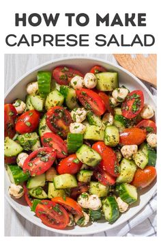 a white bowl filled with cucumber, tomatoes and other vegetables on top of a table