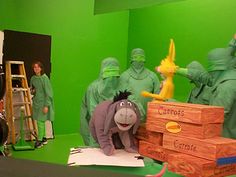 a group of people in green outfits standing around a wooden crate with a stuffed animal on it