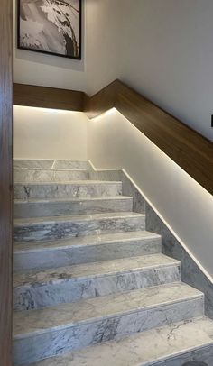 some white marble stairs with lights on the side and wood handrails above them