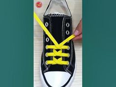 someone is tying yellow laces to a black sneaker