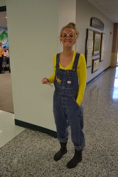 a woman in overalls and yellow shirt posing for the camera