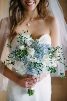 a bride holding a bouquet of blue and white flowers