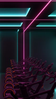 rows of stationary exercise bikes lined up in a dark room with neon lights on the ceiling