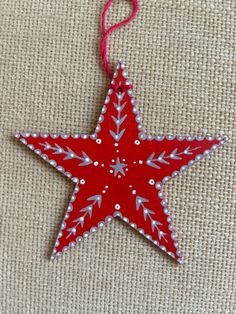 a red and white star ornament hanging from a string on a piece of fabric