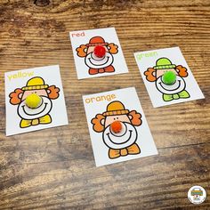 four orange and white cards with clown faces on them, sitting on a wooden table