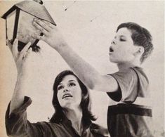 an old photo of a woman and child playing with a toy plane in the air