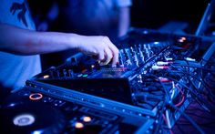 a dj mixes music in front of his mixers at a nightclub or club party