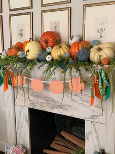 a fireplace mantel decorated with pumpkins, greenery and paper bunt garland