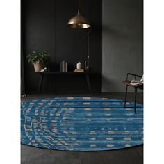 a blue rug with an abstract design in the middle and a gold lamp above it