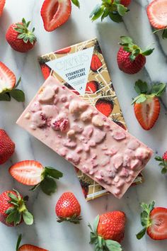 a chocolate bar with strawberries on top and some other fruit around it, sitting on a marble surface