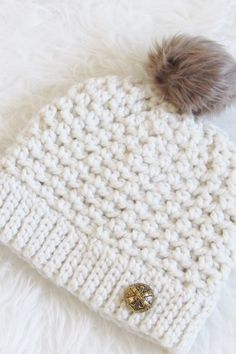 a white knitted hat with a brown pom - pom