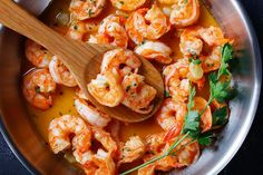 a wooden spoon in a pan filled with shrimp