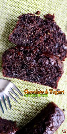 two pieces of chocolate cake sitting on top of a green cloth with a fork in it