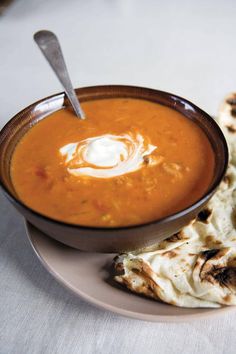 a bowl of soup on a plate with pita bread