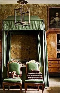 two green chairs sitting next to each other in front of a canopy bed with a teddy bear on it