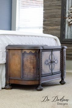 a bed sitting next to a wooden dresser on top of a carpeted bedroom floor