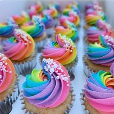 cupcakes with rainbow frosting and sprinkles are arranged in rows