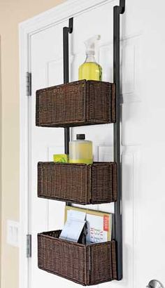 three brown baskets are hanging on the wall next to a door with soap and other items in it