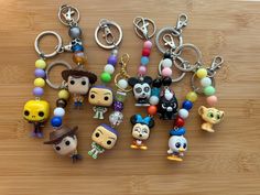 several key chains with various cartoon characters on them sitting on a wooden table next to each other