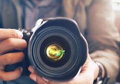 a person holding a camera in their hands with the lens pointed up to the camera