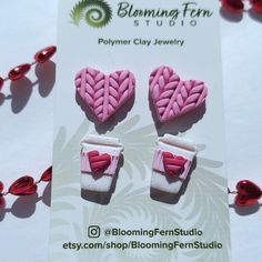 two pink and white heart shaped earrings sitting on top of a card