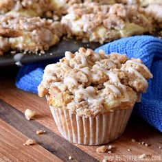 a muffin with icing sitting on top of a wooden table next to a blue towel