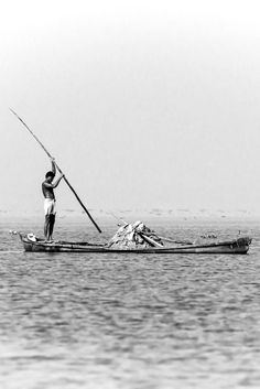 a man standing on top of a boat in the ocean holding onto a fishing pole