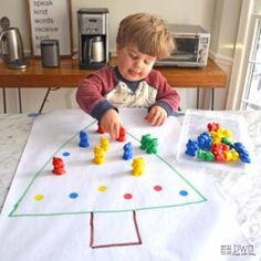 a young boy playing with toys on a table in front of a toaster oven