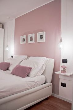 a white bed with pink pillows and two pictures on the wall above it in a bedroom