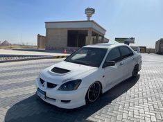 a white car parked in front of a building on the side of a brick road